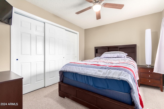 carpeted bedroom featuring a closet, a textured ceiling, and ceiling fan