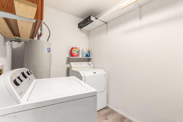 laundry room featuring water heater, washer and clothes dryer, and light wood-type flooring