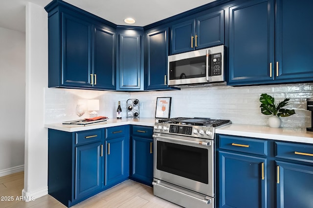 kitchen with blue cabinetry, stainless steel appliances, and tasteful backsplash