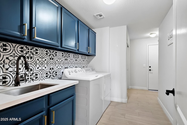 laundry room featuring separate washer and dryer, sink, cabinets, and a textured ceiling