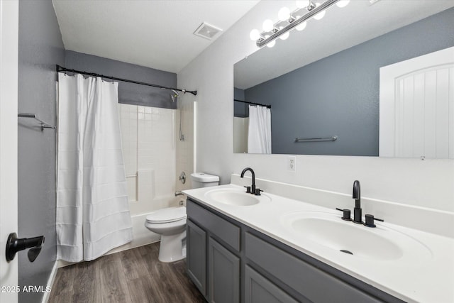 bathroom with toilet, wood finished floors, a sink, and visible vents