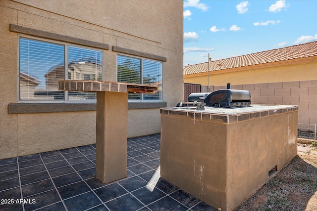 view of patio featuring a grill, an outdoor kitchen, and fence