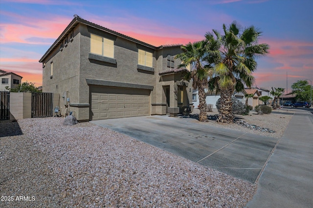 view of front of house featuring stucco siding, driveway, a tile roof, a garage, and a gate