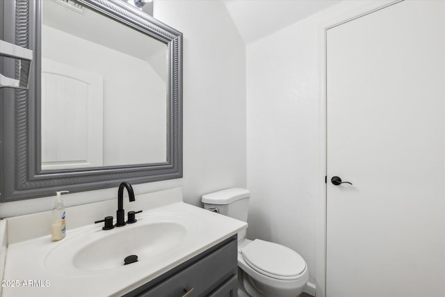 half bath featuring vanity and toilet
