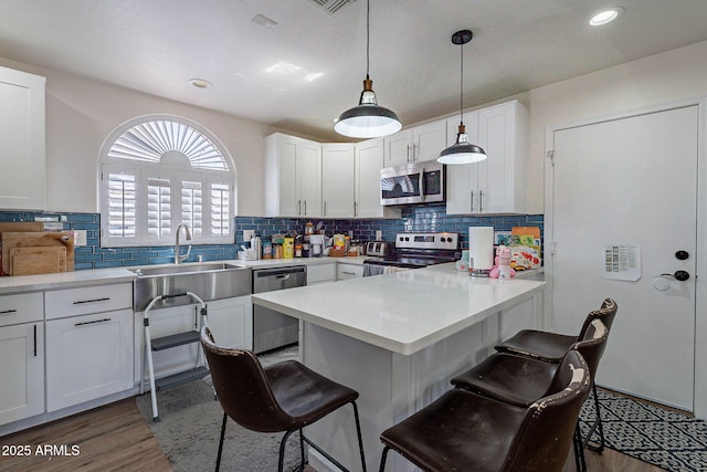 2714 E Valencia Dr, Phoenix, AZ 85042 - kitchen featuring stainless steel appliances, a breakfast bar, a peninsula, white cabinetry, and wood finished floors