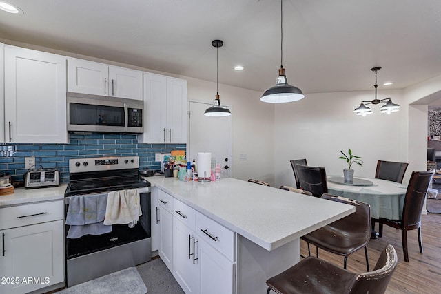 2714 E Valencia Dr, Phoenix, AZ 85042 - kitchen with stainless steel appliances, a peninsula, tasteful backsplash, white cabinetry, and recessed lighting