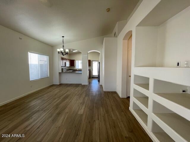 unfurnished living room featuring a notable chandelier, dark hardwood / wood-style floors, and lofted ceiling