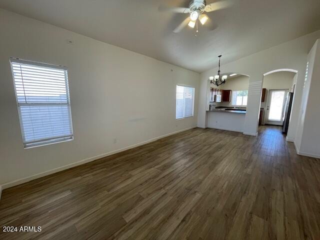 unfurnished living room with dark wood-type flooring, vaulted ceiling, and ceiling fan with notable chandelier