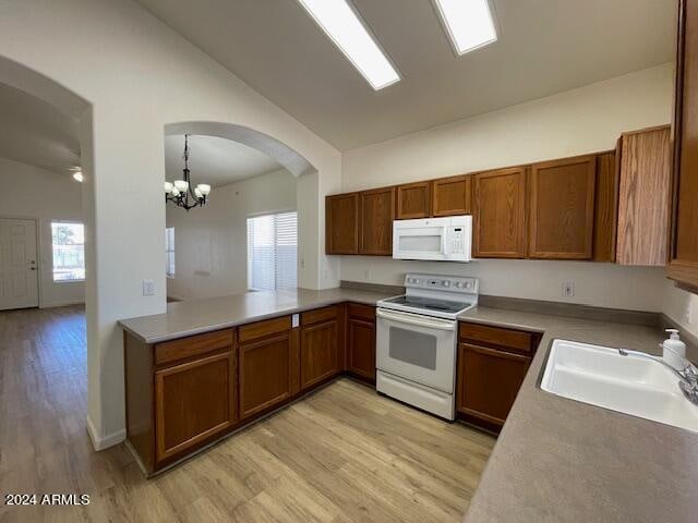 kitchen with lofted ceiling, decorative light fixtures, a wealth of natural light, and white appliances