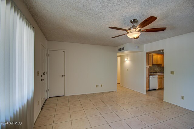 tiled spare room with ceiling fan, sink, and a textured ceiling