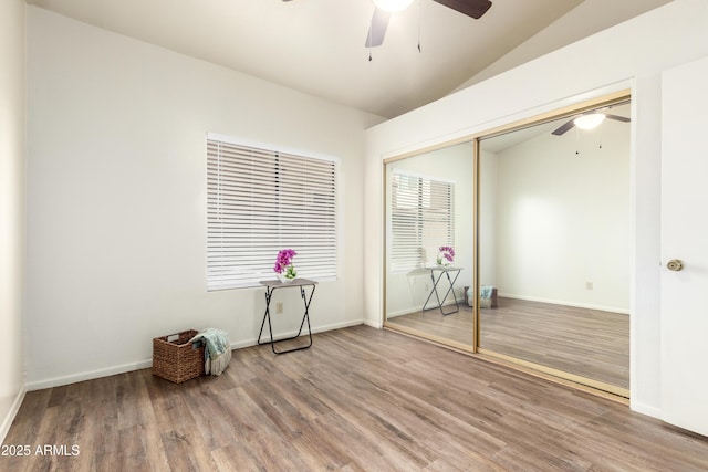 empty room featuring ceiling fan, vaulted ceiling, baseboards, and wood finished floors