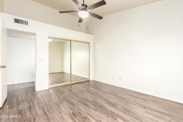 unfurnished bedroom featuring baseboards, visible vents, ceiling fan, wood finished floors, and a closet