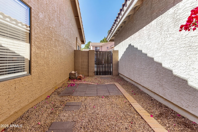 view of property exterior featuring fence, a gate, and stucco siding