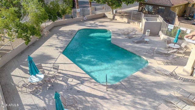 community pool with a patio area and fence