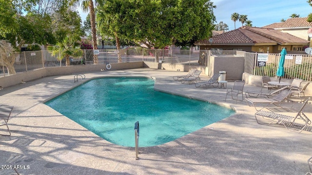 pool with a patio area and fence