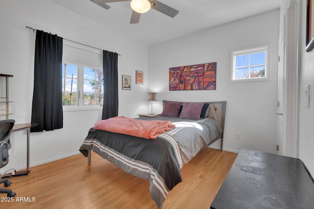 bedroom featuring ceiling fan, multiple windows, and light hardwood / wood-style flooring