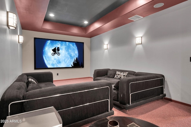 carpeted cinema room featuring a raised ceiling