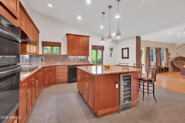 kitchen featuring a breakfast bar area, wine cooler, black appliances, a kitchen island, and decorative light fixtures