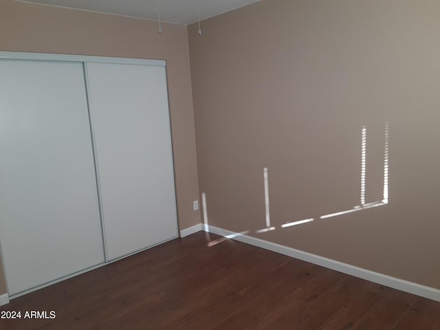 unfurnished bedroom featuring dark hardwood / wood-style floors and a closet