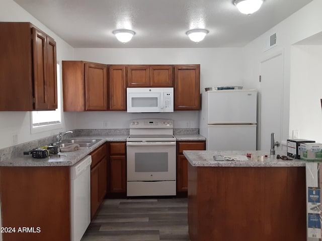 kitchen featuring white appliances, dark hardwood / wood-style floors, kitchen peninsula, and sink