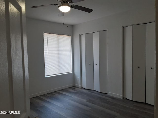 unfurnished bedroom featuring two closets, wood-type flooring, and ceiling fan