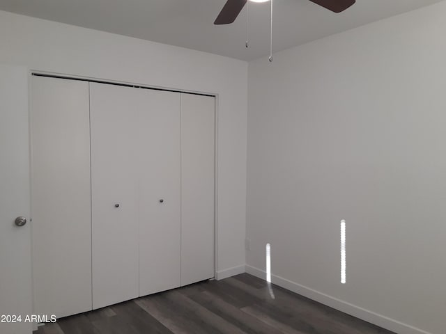 unfurnished bedroom featuring dark wood-type flooring, ceiling fan, and a closet