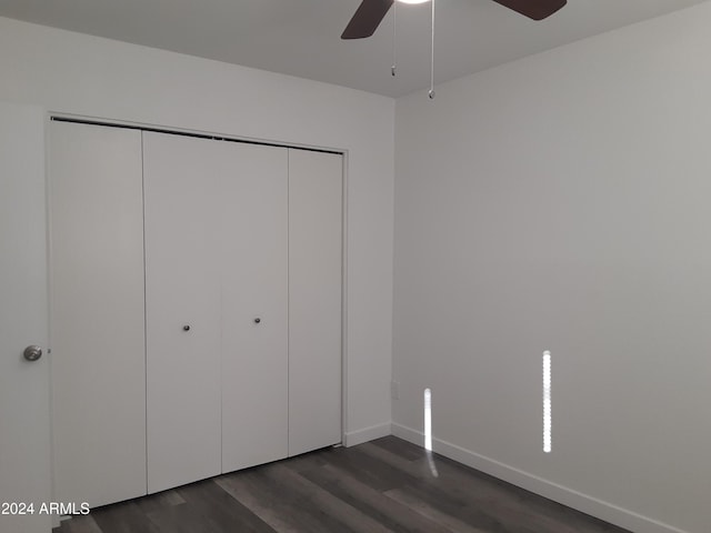 unfurnished bedroom with a closet, dark hardwood / wood-style floors, and ceiling fan