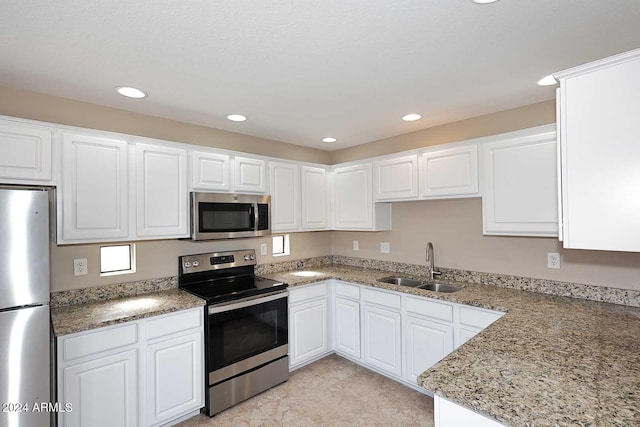 kitchen featuring white cabinets, stainless steel appliances, light stone counters, and sink