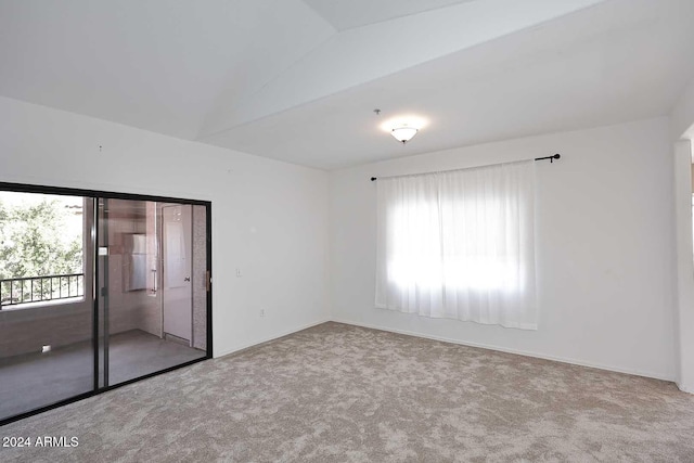 spare room featuring light colored carpet and vaulted ceiling