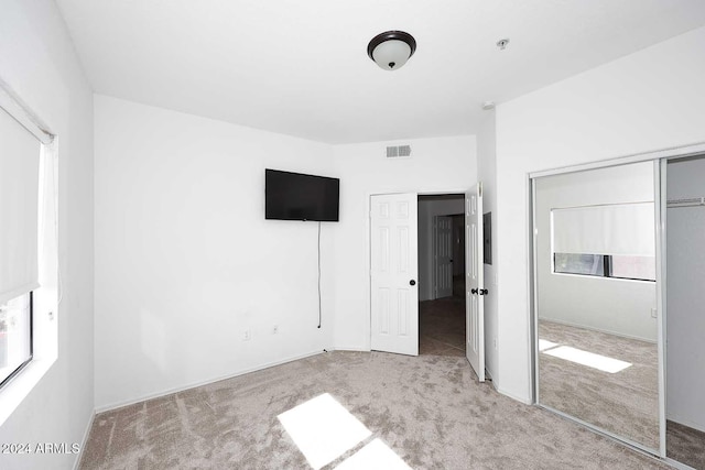 unfurnished bedroom with light colored carpet and a closet