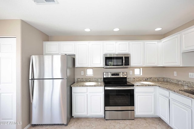 kitchen featuring white cabinetry, sink, stainless steel appliances, and light stone counters