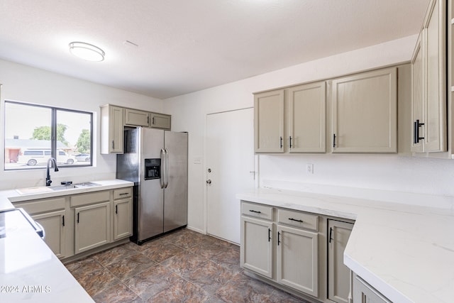 kitchen featuring gray cabinetry, light stone counters, stainless steel fridge with ice dispenser, and sink