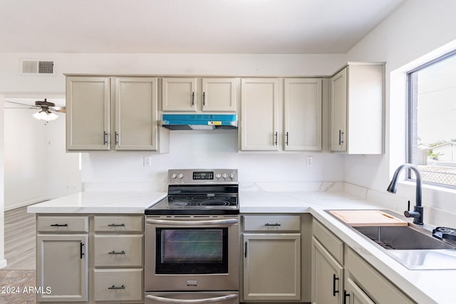 kitchen featuring electric stove, ceiling fan, sink, and cream cabinetry