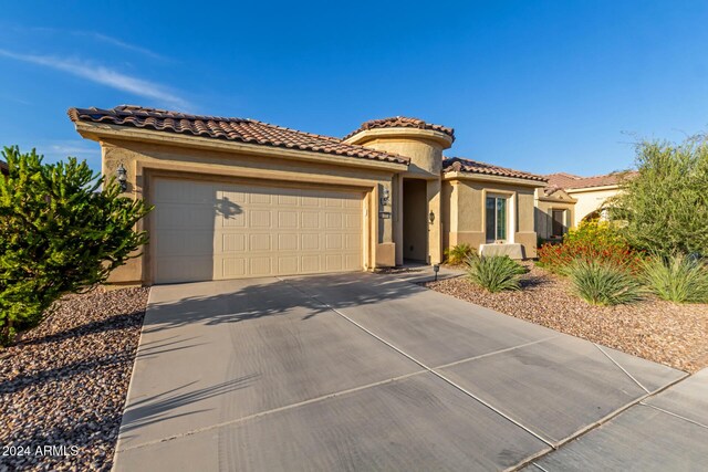 7790 W Noble Prairie Way, Florence, AZ 85132 - mediterranean / spanish home with a tile roof, an attached garage, concrete driveway, and stucco siding