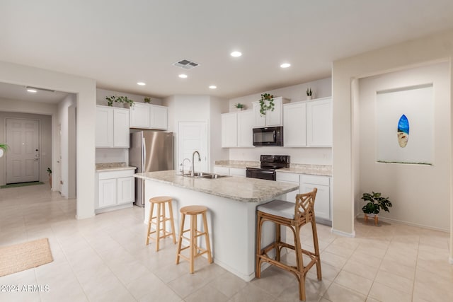 kitchen with a kitchen island with sink, a breakfast bar area, sink, black appliances, and white cabinetry