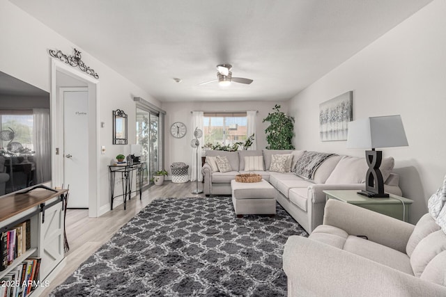living area featuring light wood-style flooring, baseboards, and ceiling fan