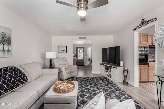 living area featuring baseboards, a ceiling fan, visible vents, and light wood-style flooring