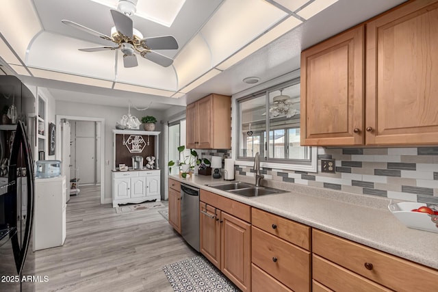 kitchen featuring light countertops, stainless steel dishwasher, a sink, light wood-type flooring, and tasteful backsplash
