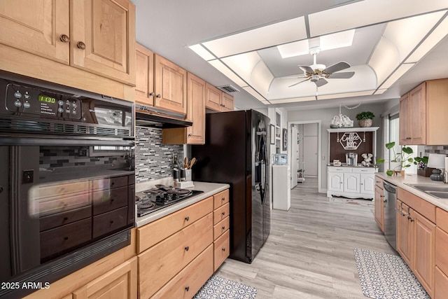 kitchen featuring a tray ceiling, visible vents, decorative backsplash, under cabinet range hood, and black appliances