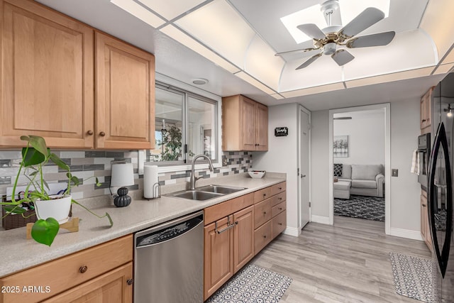kitchen with light countertops, baseboards, stainless steel dishwasher, and a sink