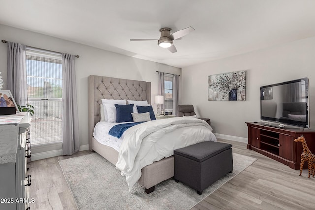 bedroom featuring light wood finished floors, a ceiling fan, baseboards, and multiple windows