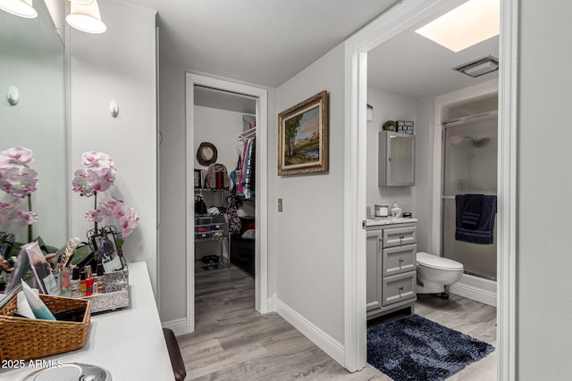 bathroom with wood finished floors, a stall shower, vanity, baseboards, and visible vents