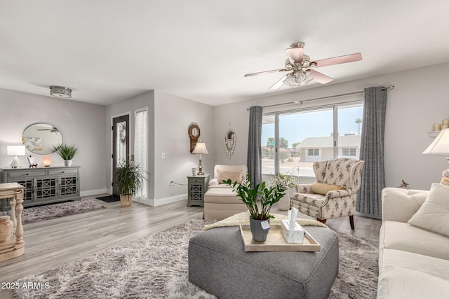 living room with ceiling fan, baseboards, and wood finished floors
