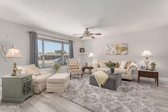 living room with light wood-style floors, baseboards, and ceiling fan