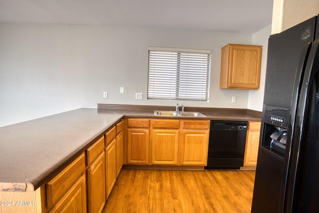 kitchen featuring kitchen peninsula, sink, light hardwood / wood-style flooring, and black appliances