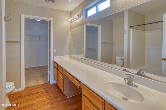 full bathroom featuring vanity, bathing tub / shower combination, hardwood / wood-style flooring, toilet, and a textured ceiling