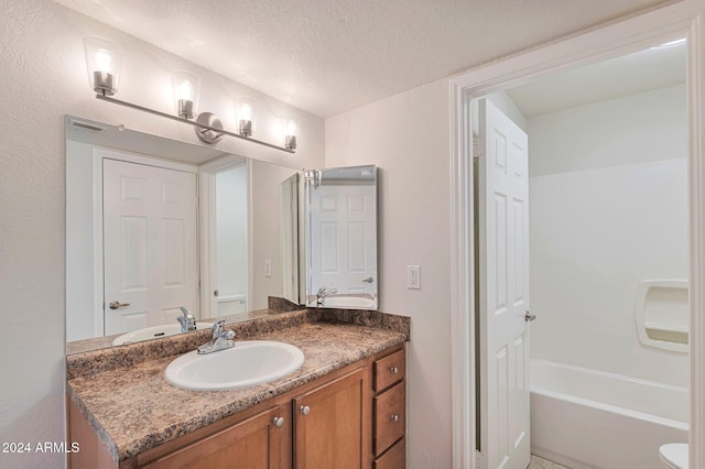 bathroom featuring a washtub, a textured ceiling, and vanity