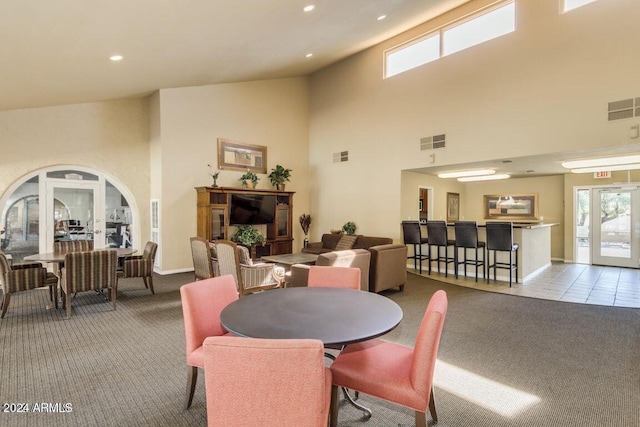 dining area featuring light carpet, french doors, and a high ceiling