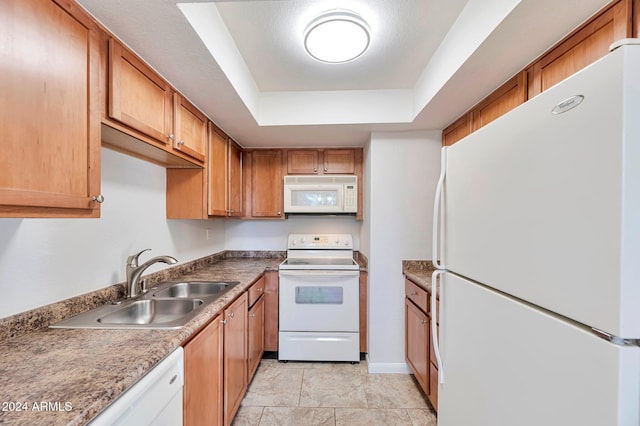 kitchen featuring a tray ceiling, sink, and white appliances