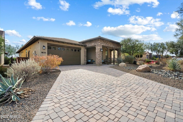 view of front of home featuring decorative driveway, an attached garage, and stucco siding